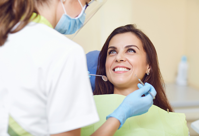 Woman in the dental chair grinning at her dentist
