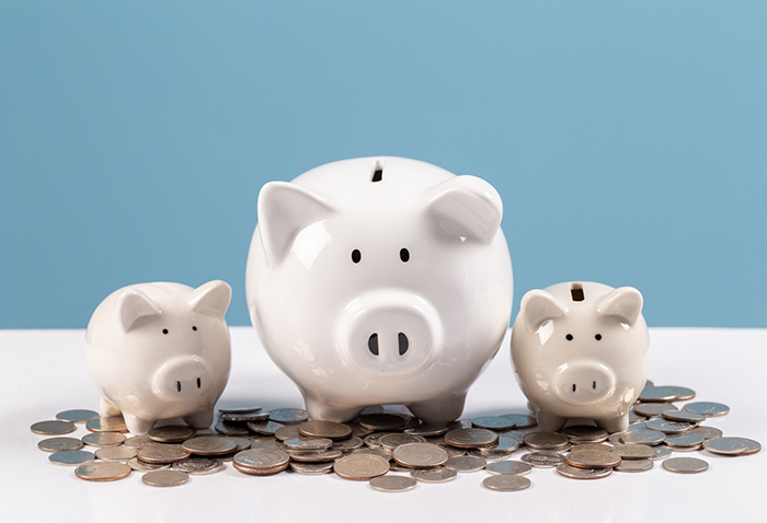 Three white piggy banks next to a pile of coins
