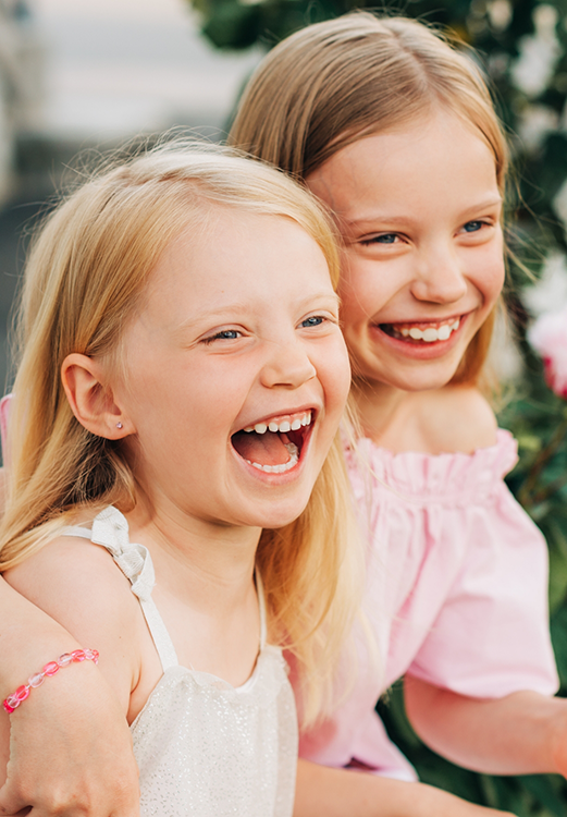 Two young girls laughing while visiting their children's dentist in Madison
