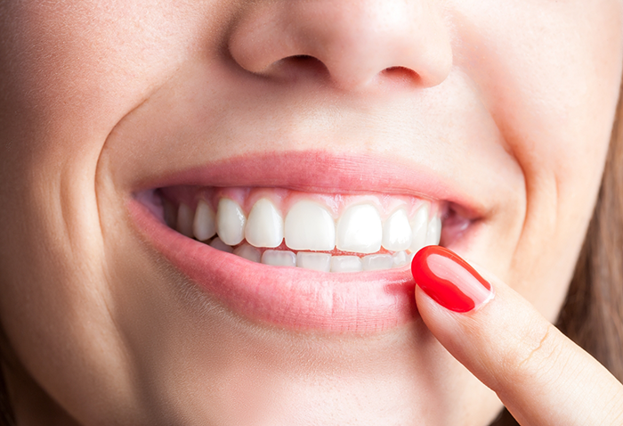 Person with flawless teeth pointing to their smile