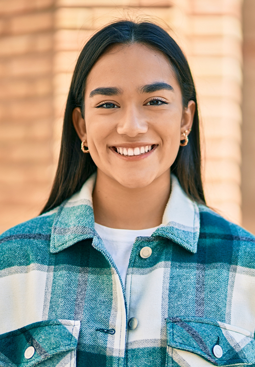 Woman in a plaid shirt smiling after restorative dentistry in Madison
