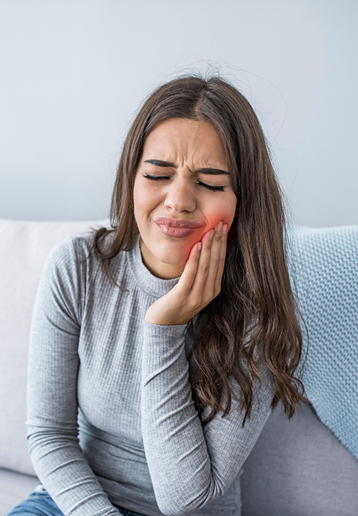 Woman holding her cheek in pain before seeing an emergency dentist in Madison