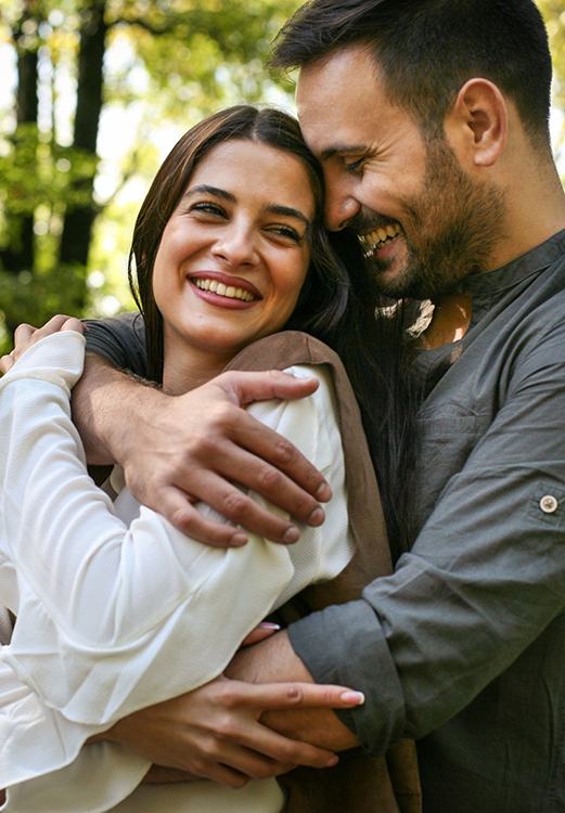 Man and woman embracing outdoors and smiling after cosmetic dentistry in Madison