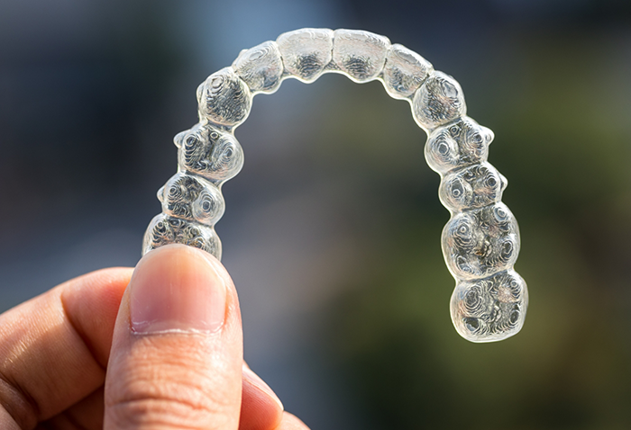 Close up of a hand holding a clear aligner
