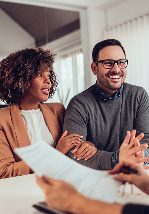 Man and woman sitting across a desk from someone looking at paperwork